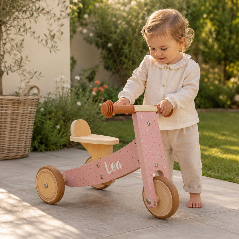 Kleinkind mit grünem personalisiertem Holz-Dreirad mit Name Lean als Geschenk zum 1. Geburtstag im Garten
