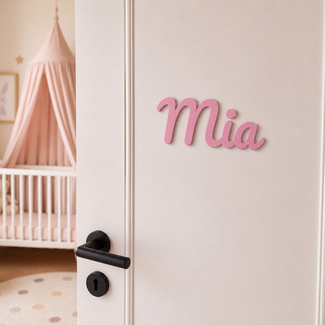 Personalisiertes Türschild Mia in Rosa an weißer Kinderzimmertür mit rosa Babyzimmer im Hintergrund