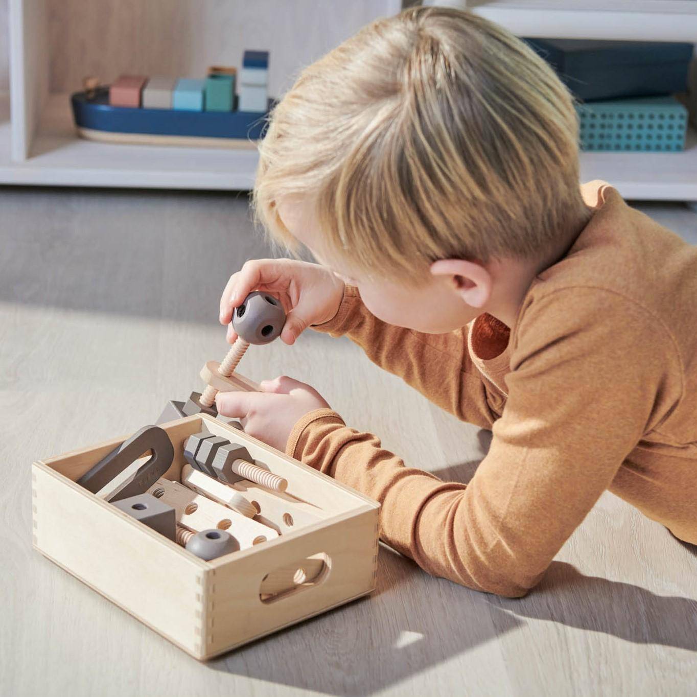 Kind spielt mit Werkzeugkoffer aus Holz und Kinderwerkzeug für kreatives Rollenspiel