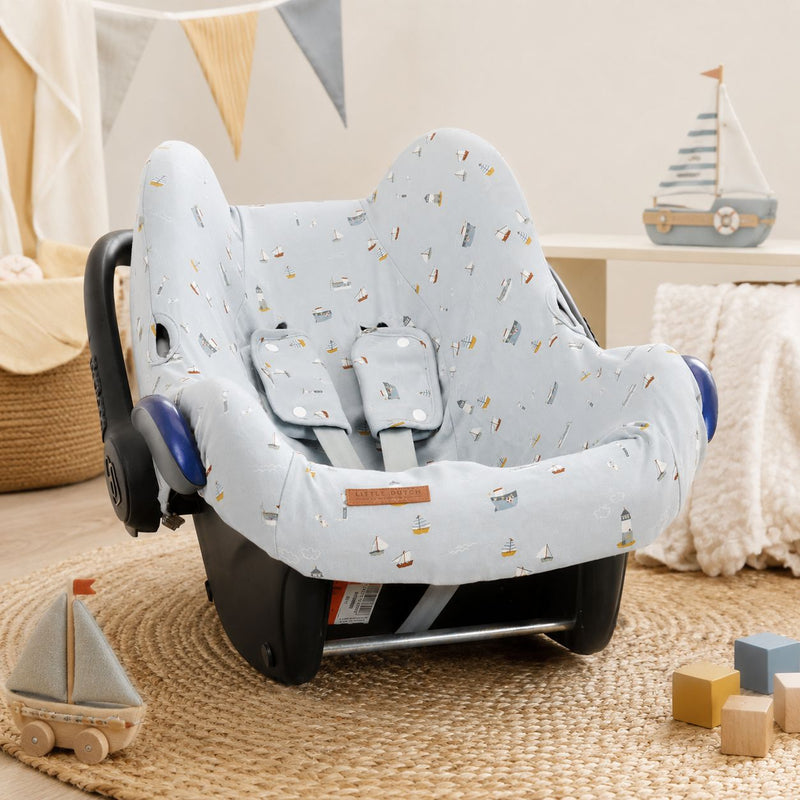 Hellblauer Babyschalenbezug mit maritimem Design auf einer Maxi-Cosi Babyschale im liebevoll eingerichteten Babyzimmer – atmungsaktiver Baumwollbezug für Babyschalen der Gruppe 0+ und komfortable Autofahrten mit Baby.