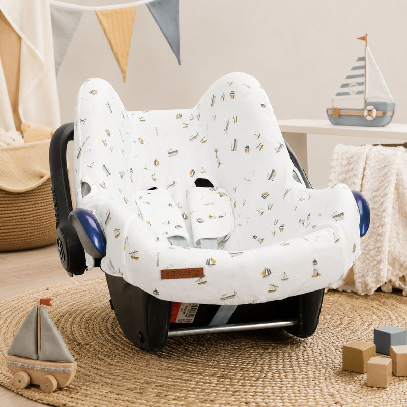 Weißer Babyschalenbezug mit maritimem Design auf einer Maxi-Cosi Babyschale in einem gemütlichen Babyzimmer – weicher Baumwollbezug für Babyschalen der Gruppe 0+.