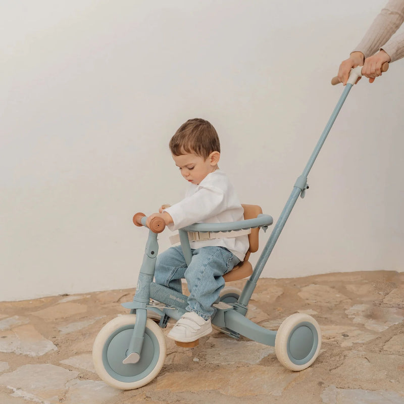 Kind sitzt auf dem Little Dutch Tricycle 4-in-1 in Blau mit Schubstange. Das Schiebedreirad bietet Sicherheit, Komfort und wächst vom Dreirad zum Laufrad für Kinder ab 1 Jahr mit.