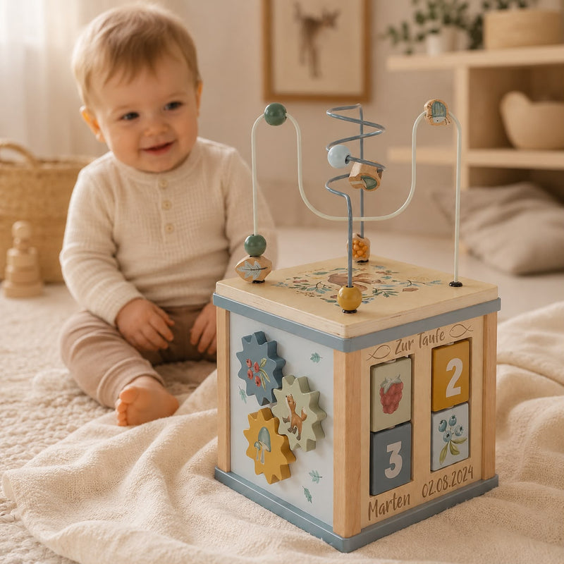 Personalisierter Motorikwürfel zur Taufe mit Name und Datum von Schmatzepuffer – hochwertiges Holzspielzeug im warmen Lifestyle-Fotoshooting mit Baby im Hintergrund, besonderes Taufgeschenk und personalisierte Erinnerung