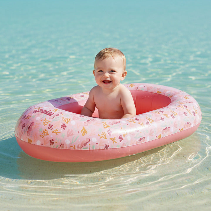 Baby sitzt in aufblasbarem Schlauchboot im Wasser – sicherer Badespaß für Kinder im Sommer und Urlaub